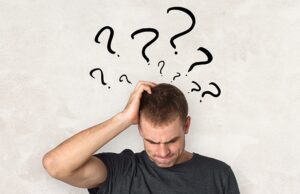 A man with his head held up in front of some question marks.